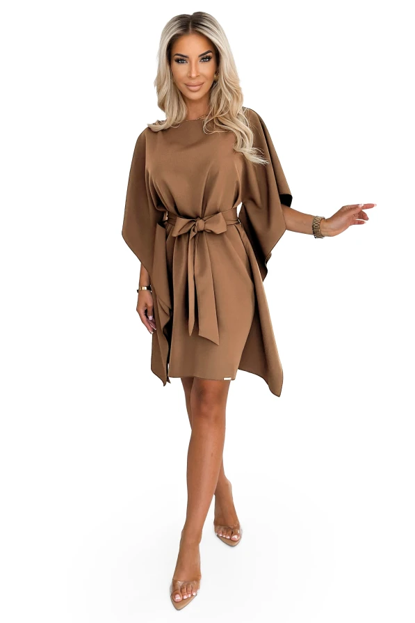 Modelka prezentuje stylową sukienkę Numoco z szerokimi rękawami i paskiem w talii w odcieniu karmelowym – modna kreacja polskiej produkcji.