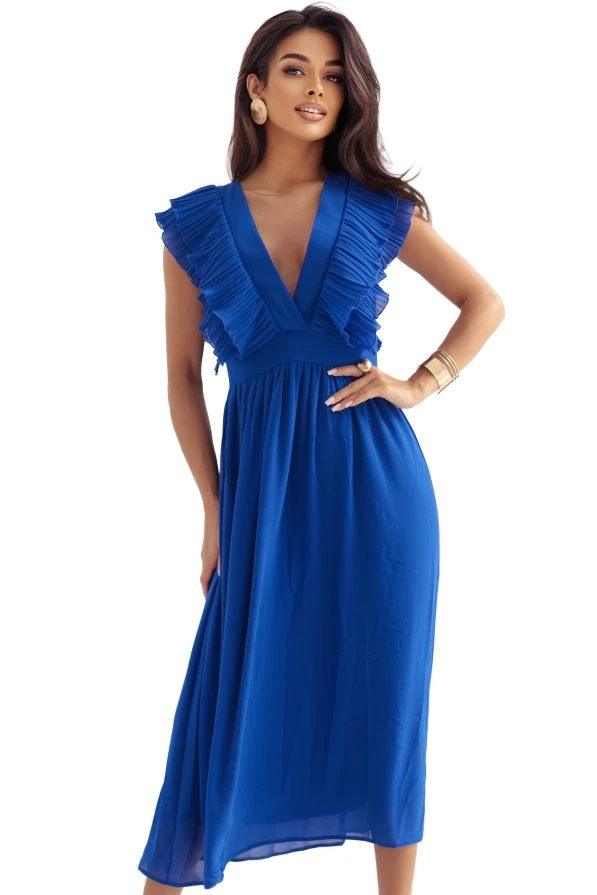 Kobieta w eleganckiej, chabrowej sukni midi z falbanami przy dekolcie i rozkloszowanym dołem, pozująca w jasnym, stylowym wnętrzu. Limitowana edycja sukienki marki Numoco, produkt polski.