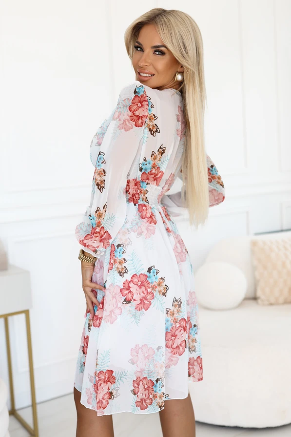 Modelka prezentuje zwiewną kopertową sukienkę w kwiaty z długim, transparentnym rękawem i głębokim dekoltem; lekka, romantyczna stylizacja idealna na wiosnę i lato, produkt polski marki Numoco.