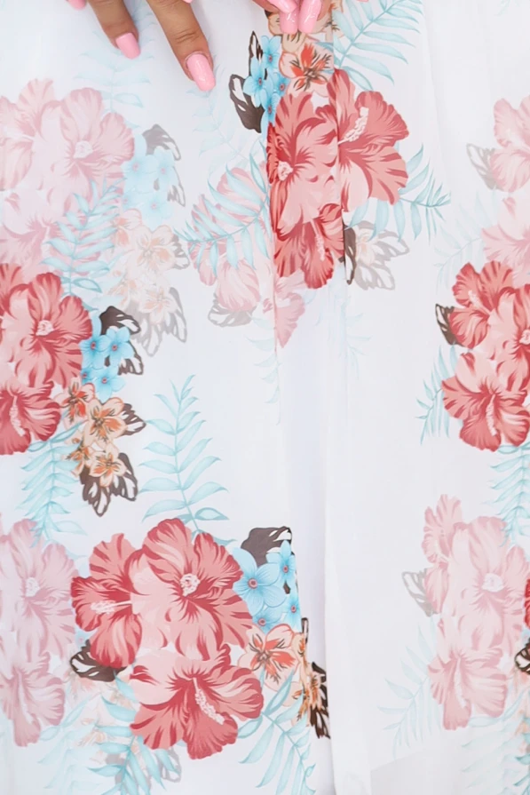 Modelka prezentuje zwiewną kopertową sukienkę w kwiaty z długim, transparentnym rękawem i głębokim dekoltem; lekka, romantyczna stylizacja idealna na wiosnę i lato, produkt polski marki Numoco.