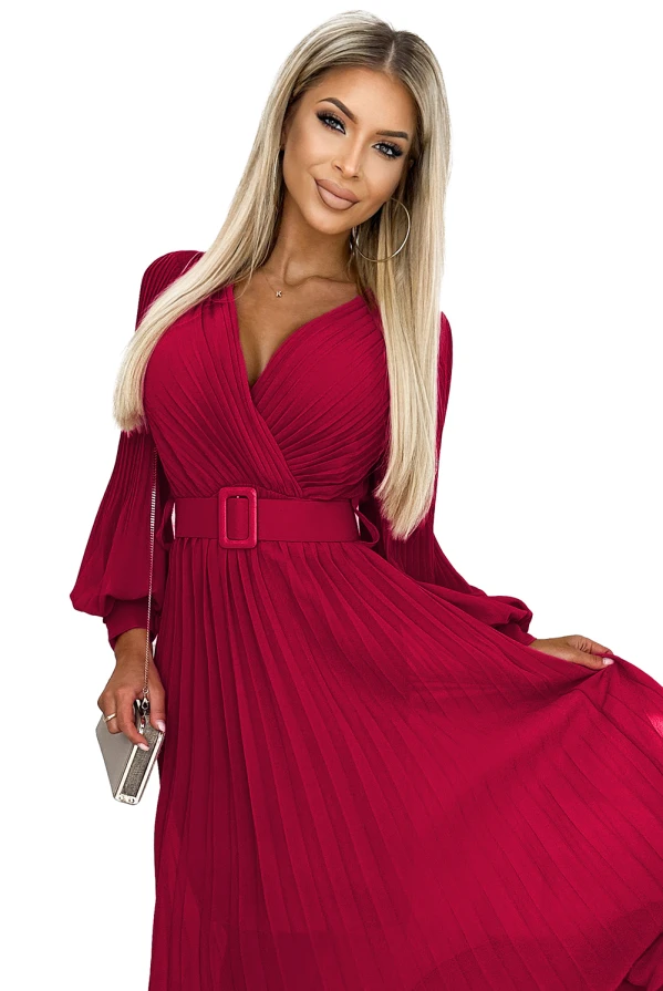 На снимката е изобразена елегантна дамска рокля в наситено червен цвят с дълги ръкави и плисирана пола. Роклята е с V-образно деколте и колан, който подчертава талията.