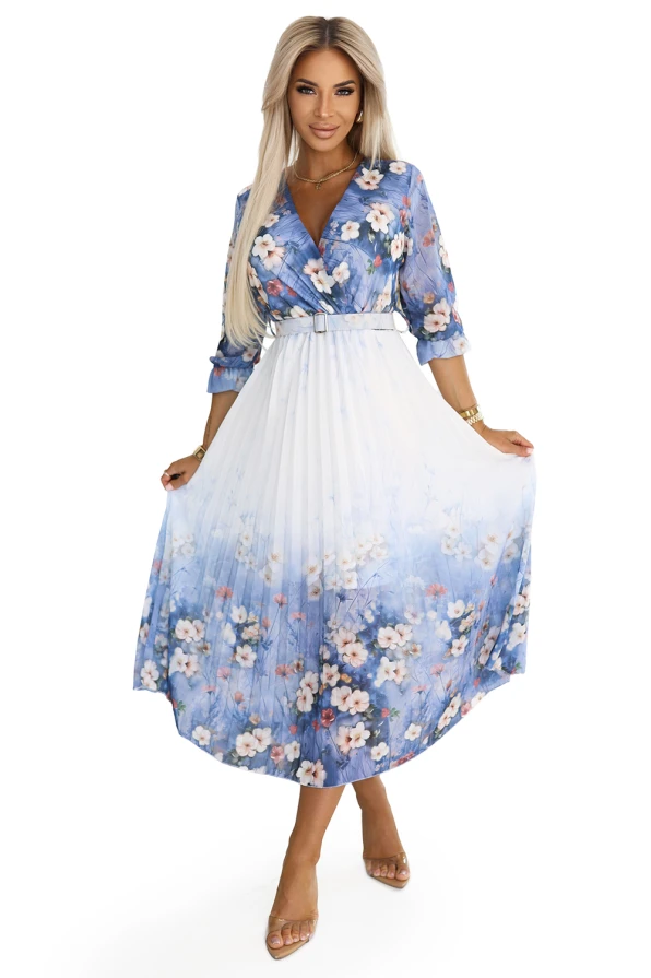 Plisowana sukienka midi z kopertowym dekoltem i kwiatowym wzorem w odcieniach niebieskiego i bieli. Modelka prezentuje sukienkę Numoco Basic – elegancką, lekką kreację idealną na wiosnę i lato.